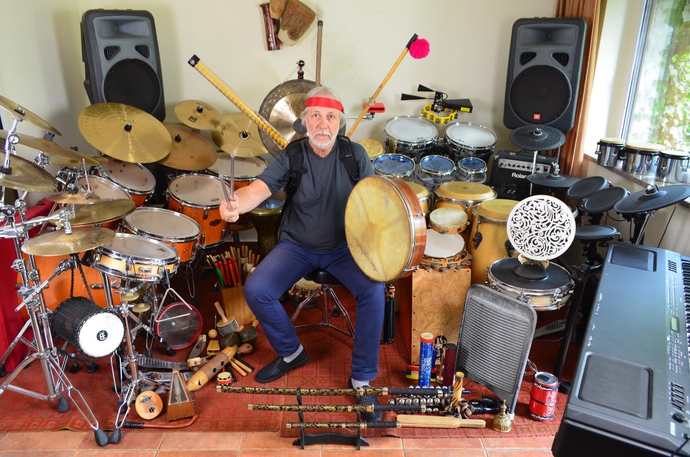 Obraz przedstawiający rozłożone instrumenty na całej szerokości pokoju: zestawy perkusyjne, kongi, talerze, rototomy, cajon i wiele innych.

Na środku pokoju znajduje się prowadzący udający wojownika z tarczą z bodhranu i dwoma pałeczkami zamiast mieczy.